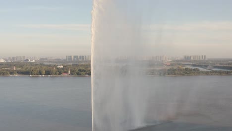 sunrise, golden hues, reflection across the songhua river, city waking up in shadows, clear sky and famous 160m high water fountain casting mist in the sun rays