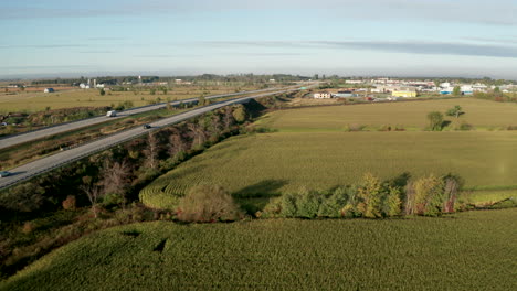 Cars-travel-on-highway-toward-small-farming-community-in-the-distance