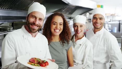 team of chefs holding food plate in commercial kitchen