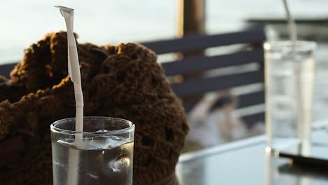 a refreshing iced beverage with a straw, set against a blurred outdoor background.
