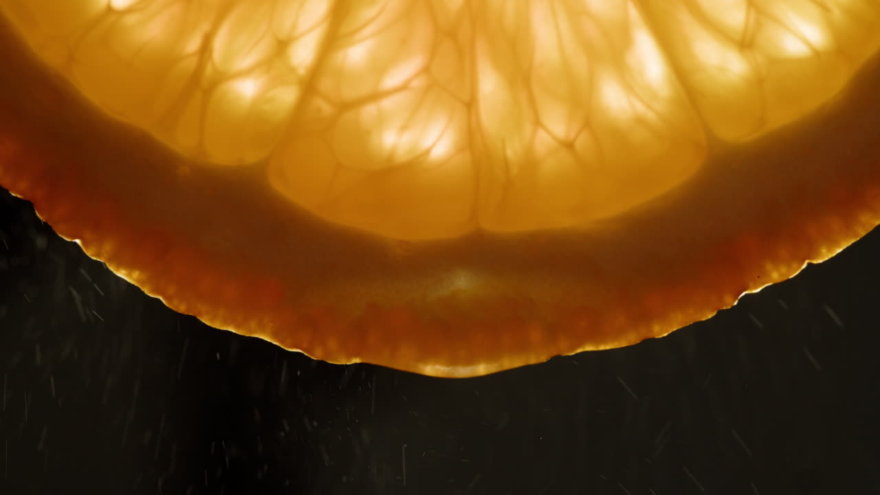 Close-up of a Fresh Orange Slice with Water Droplets Falling