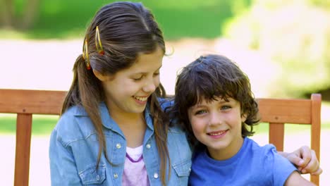 brother and sister embracing on park bench