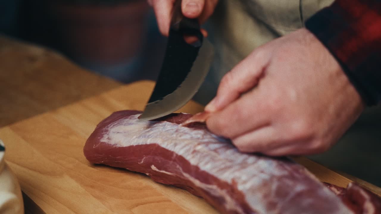 un primer plano de una persona usando un cuchillo para cortar la carne en una tabla de cortar de madera