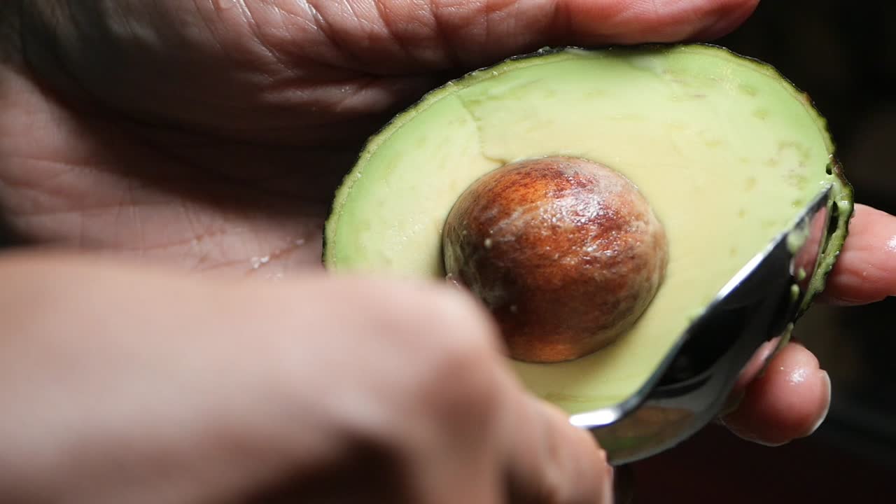 Primo piano di mani che tengono in mano mezzo avocado