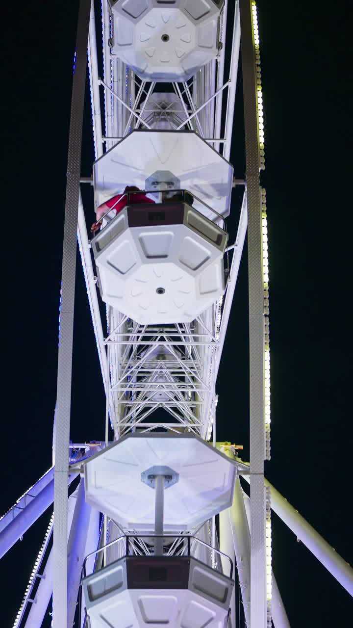 View of an illuminated ferris wheel on the beach in the evening in Antibes, France. Vertical