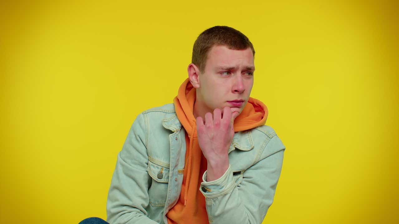 Thoughtful student man rubbing his chin with pensive expression, pondering a solution, question