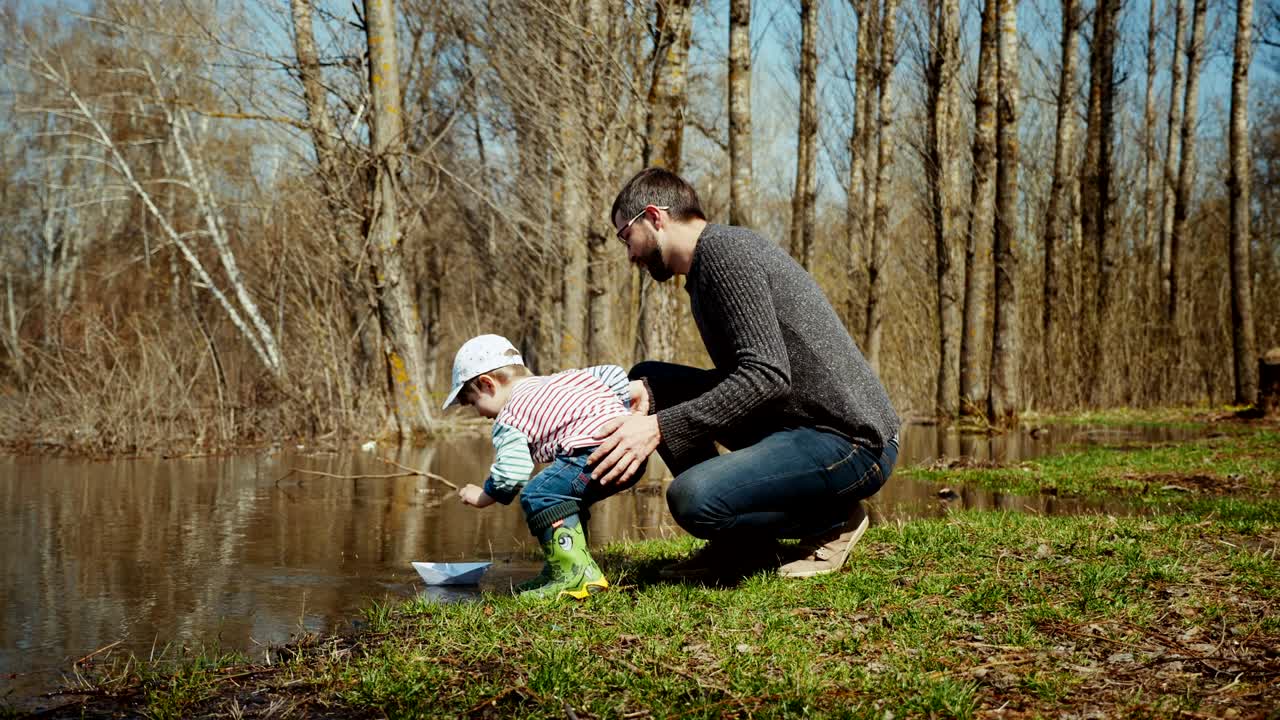 una familia joven está navegando en un barco de papel de juguete en el agua