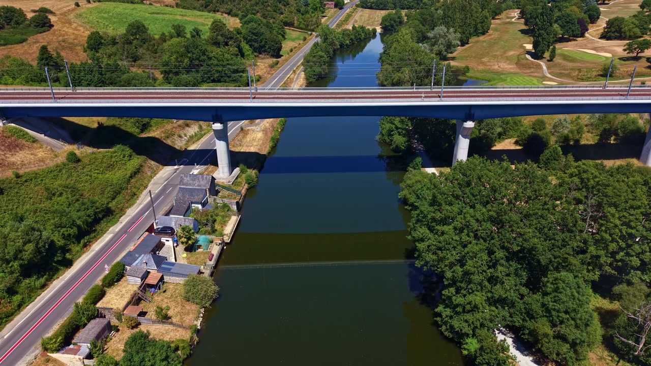 Moderni betoninen silta rauhallisen Mayenne-joen yli, vihreiden puiden ympäröimänä Ranskassa. Ilmakuva dronella.