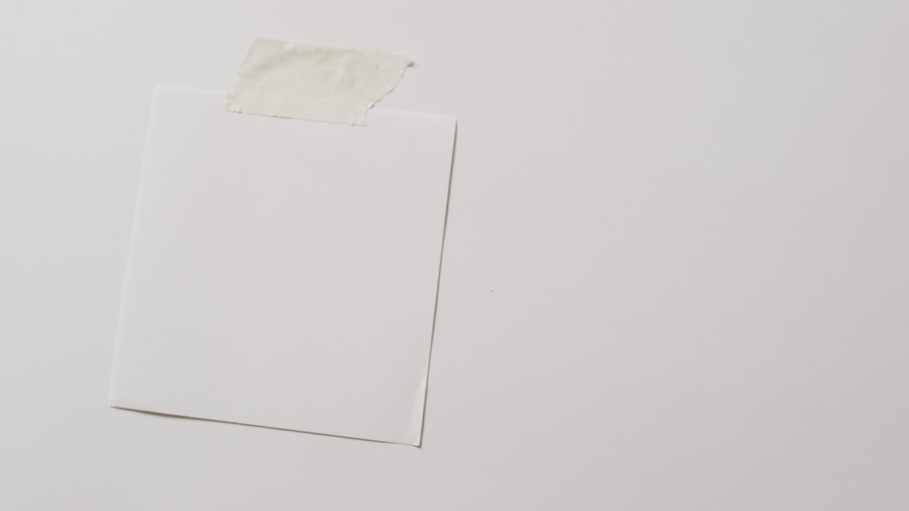 video de un primer plano de una nota de nota blanca con espacio de copia pegado a un fondo blanco