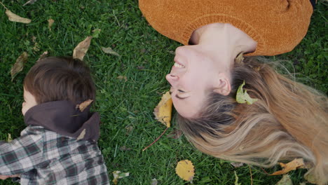 A-happy-mother-and-child-play-together,-lie-on-the-grass-in-the-park.-Asian-kid-laughs-happily