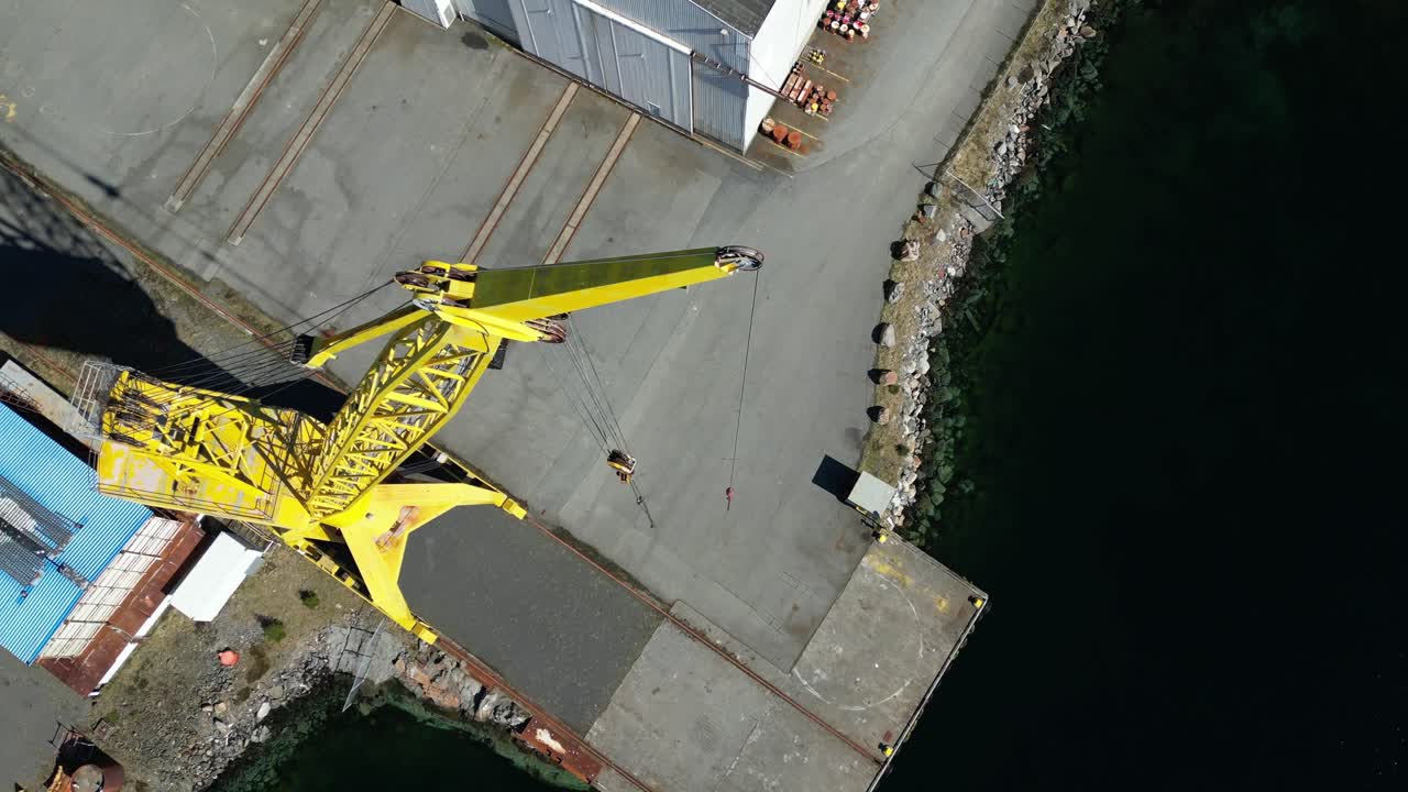 drone desciende en el lado de una grúa alta en un astillero en desuso