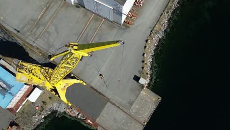 drone descends on the side of a tall crane at a disused shipyard