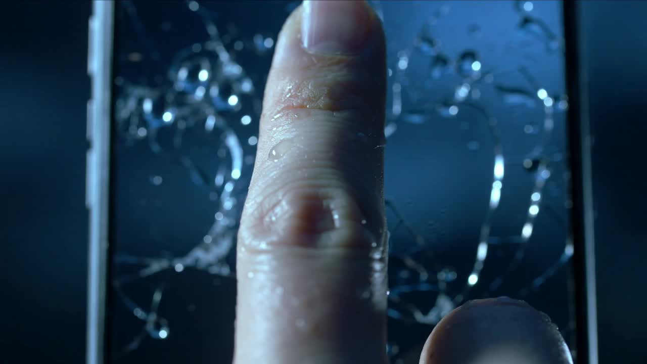 Touching index fingertip shifting on wet shattered phone screen in studio, revealing bright logo