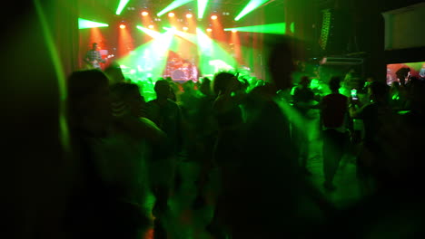 vibrant concert scene with energetic crowd illuminated by green stage lights and dynamic atmosphere