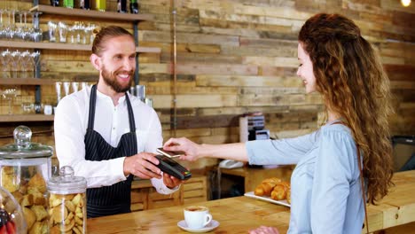 mujer pagando facturas a través de un teléfono inteligente utilizando tecnología nfc
