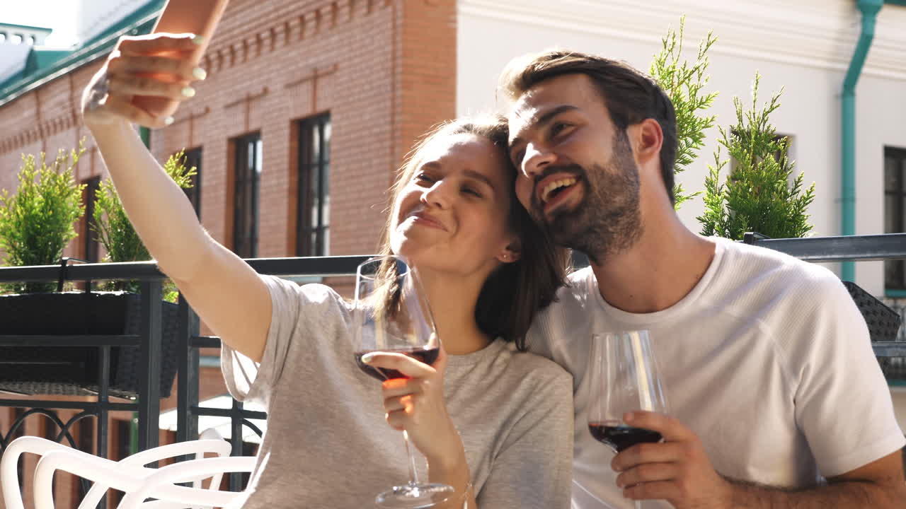 Coppia che si scatta un selfie su un balcone mentre degusta vino