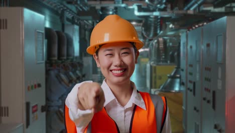 female engineer pointing at the camera in a factory