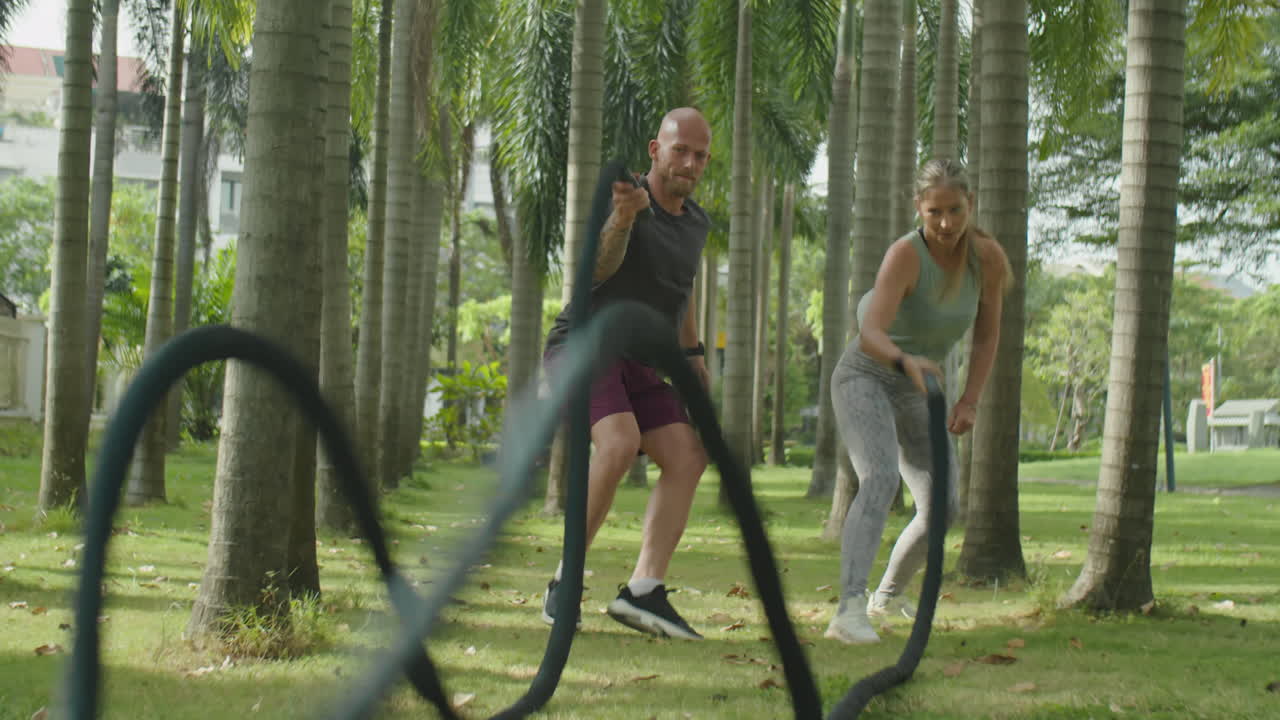 Athletic Couple Doing Battle Rope Waves in Park