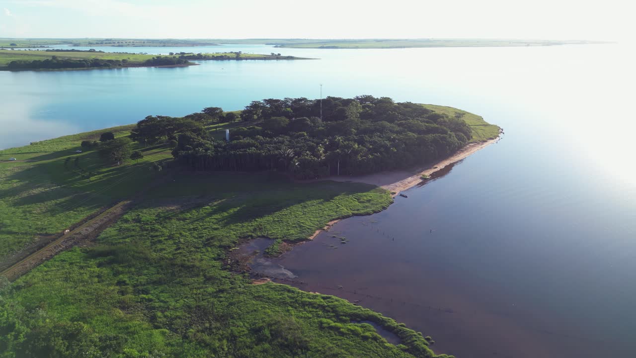 High key aerial: Dirt road leads to eco-tourism island on Brazil lake