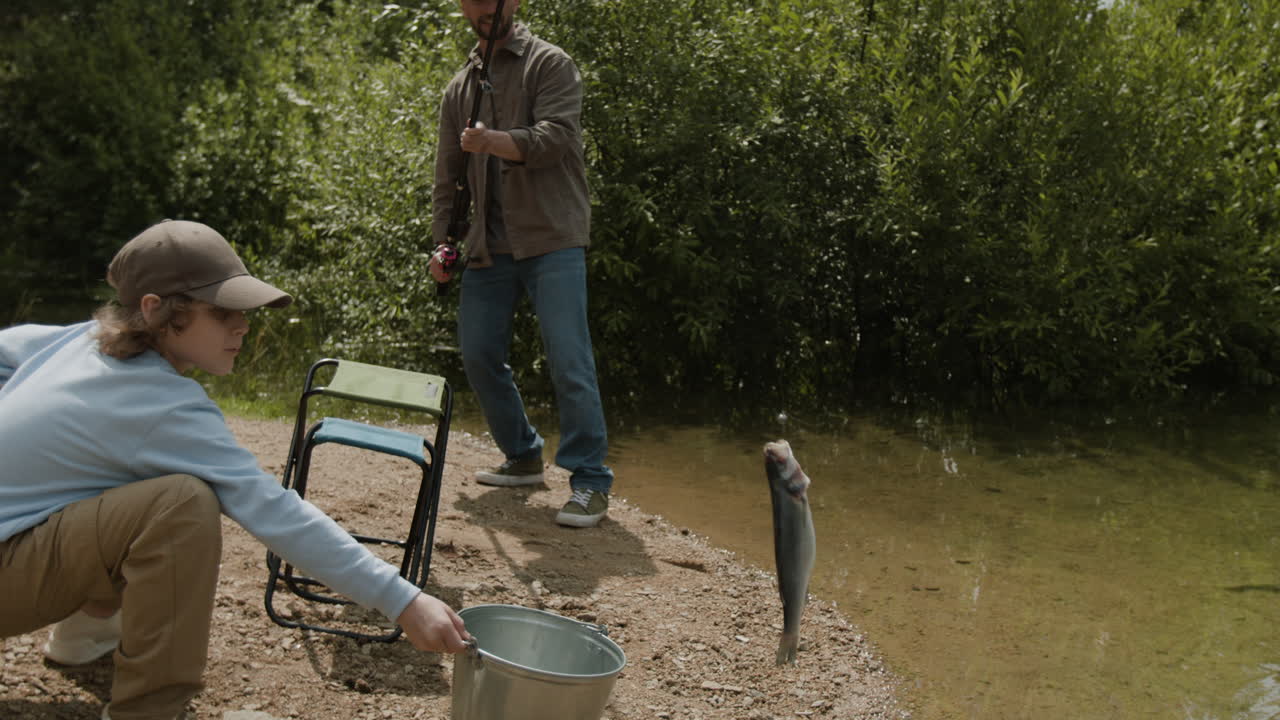 отец и сын вместе ловят рыбу.