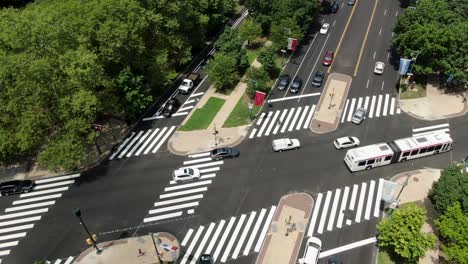 aerial of city public transit, extended bus crossing through urban intersection and multiple lanes of traffic, ben franklin parkway in philadelphia, flags from around the world along street