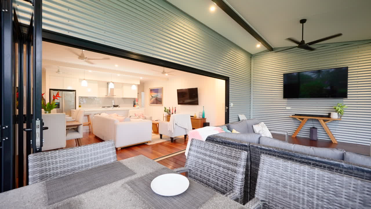 pátio ao ar livre com mesa parcialmente encenada com uma tigela de frutas e plano de piso aberto conectando a sala de estar à varanda