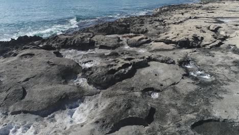 Drone-Volando-Bajo,-Sobre-Roca-Volcánica-En-La-Costa-De-Ko-Olina,-Hermoso-Mar-Cristalino,-Hawaii