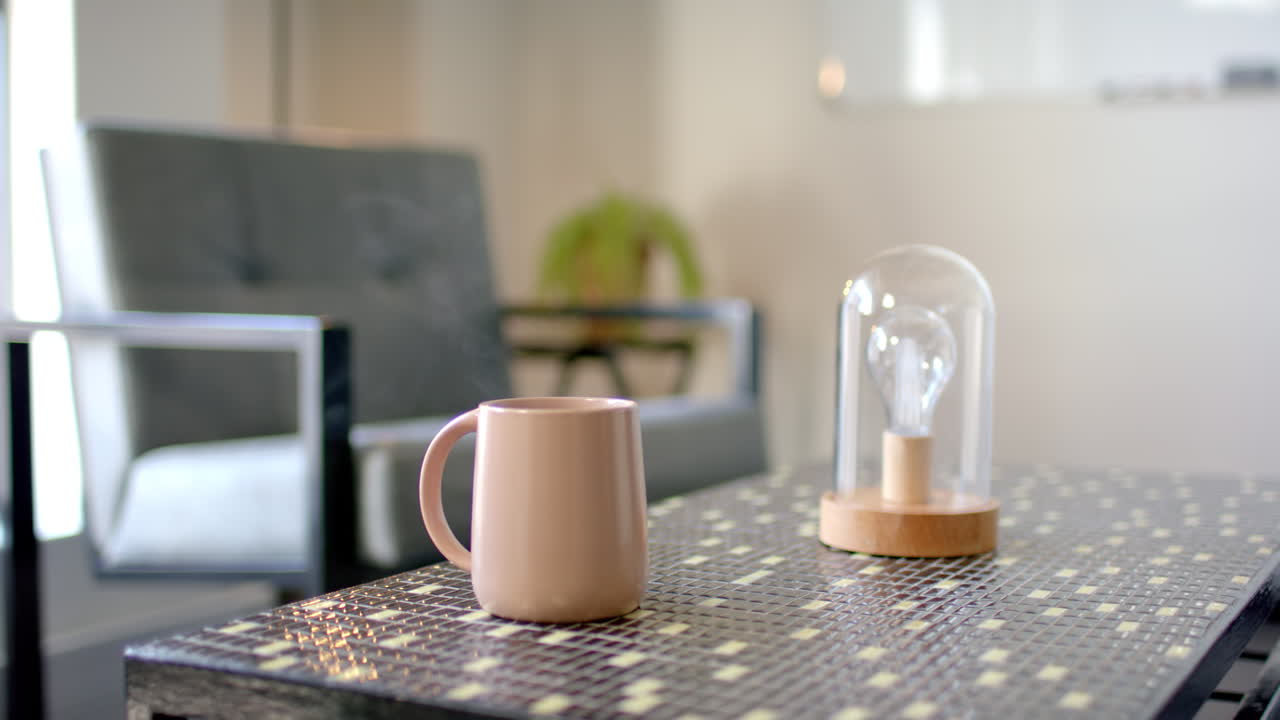 Pink coffee mug and glass dome with light bulb on modern office table, copy space