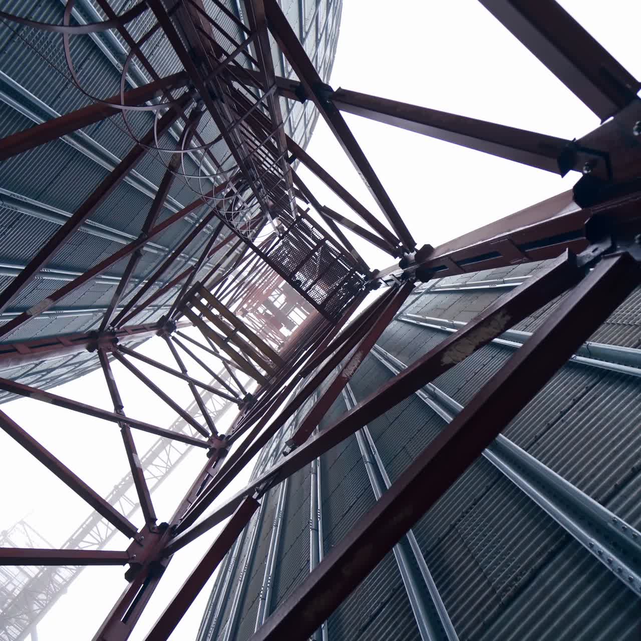 Metal towers on industrial plant.. Steel construction on a modern agricultural factory with grain elevators on sky background