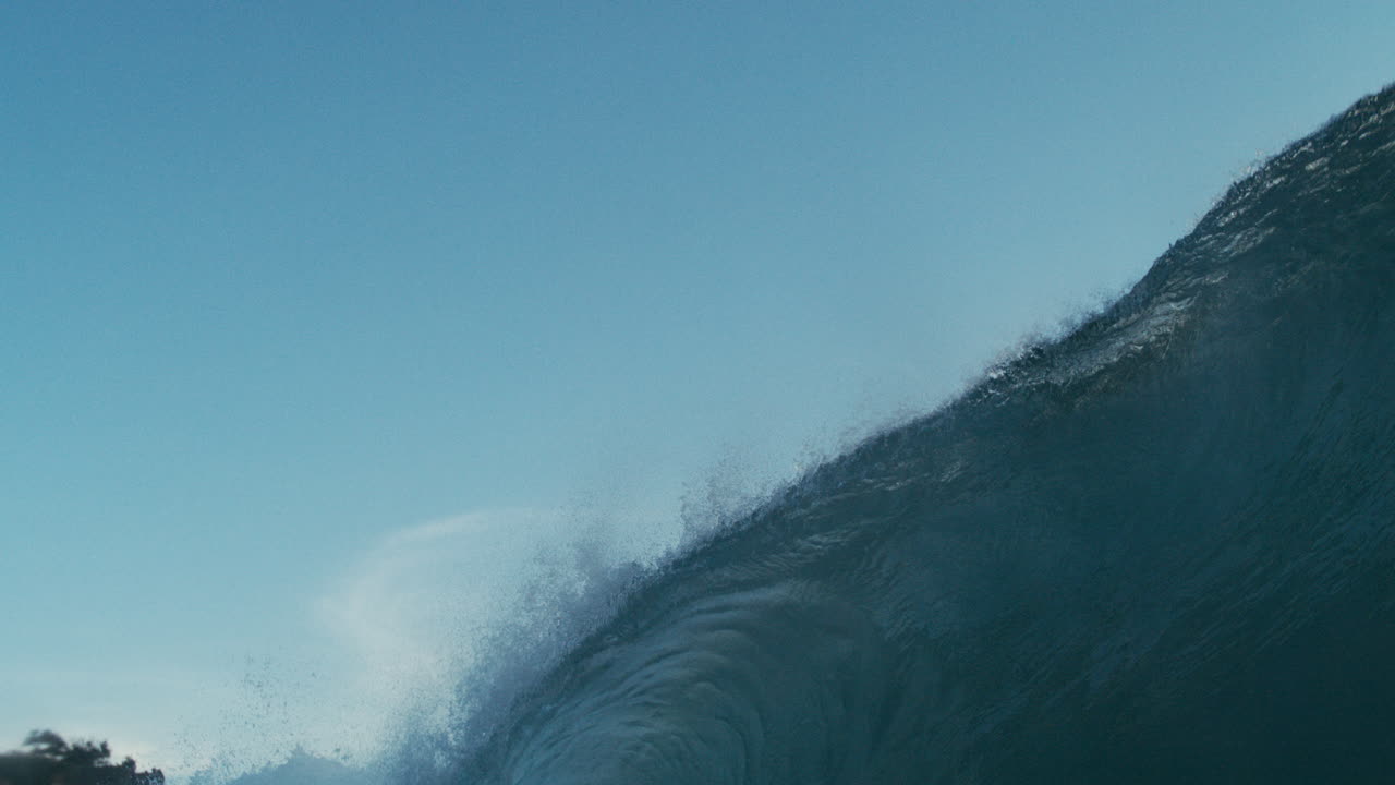 Curling wave in deep ocean, rolling with power and form across empty sea, lip throws mist into air off top, backdrop