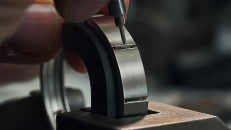 close-up of a watchmaker's hand working on a metal watch bracelet