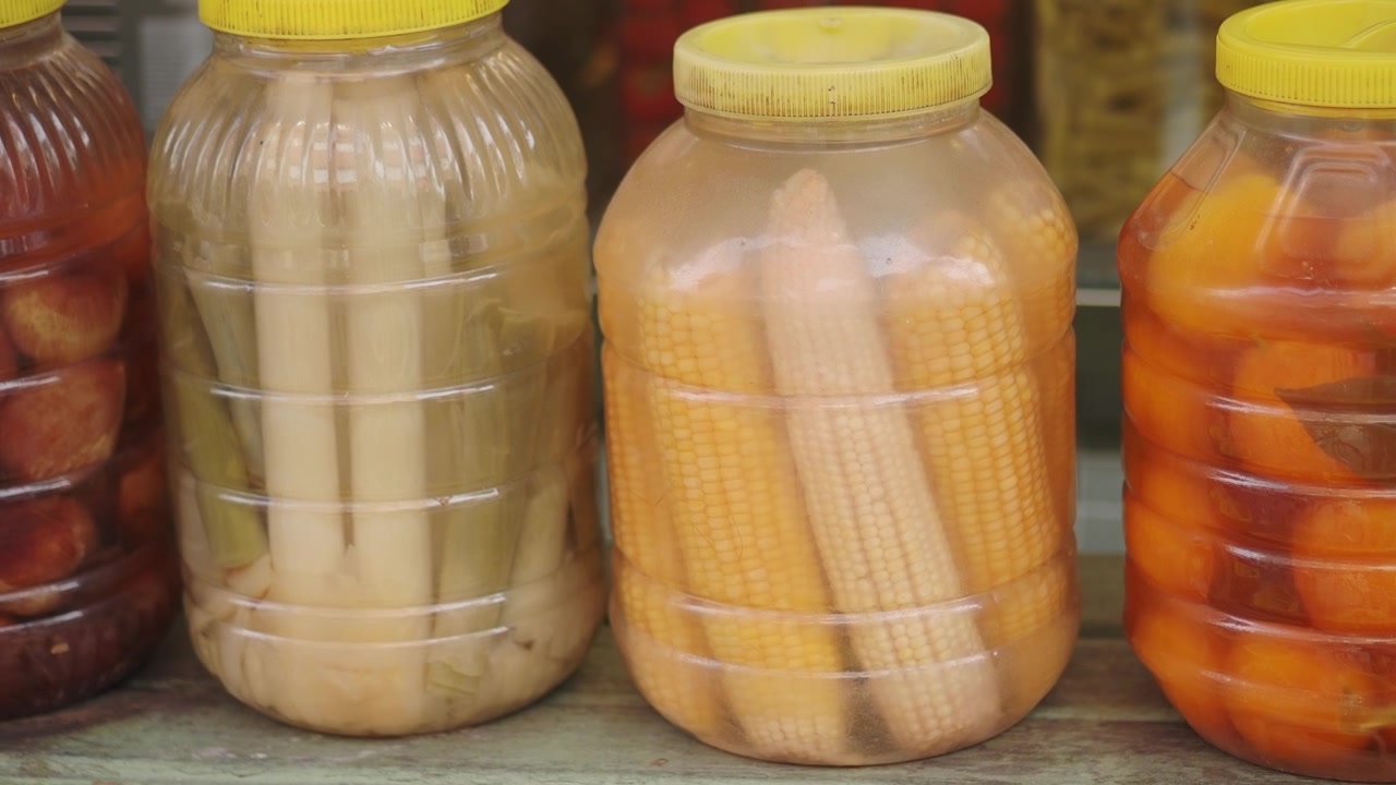 Verduras encurtidas variadas en frascos de plástico en un estante