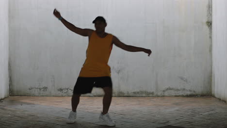 Hombre-Bailando-Joven-Feliz-Bailarín-Callejero-Realizando-Varios-Movimientos-De-Baile-De-Estilo-Libre-En-Forma-De-Hombre-De-Raza-Mixta-Practicando-En-Un-Almacén-Sucio-Con-Chaleco-Amarillo