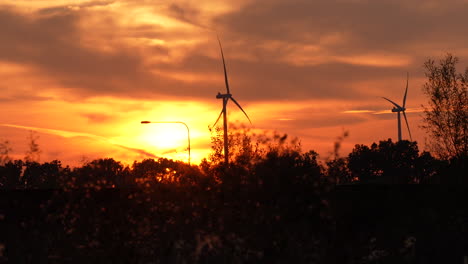 wind turbines silhouetted against a vibrant sunset, with a streetlamp in the foreground