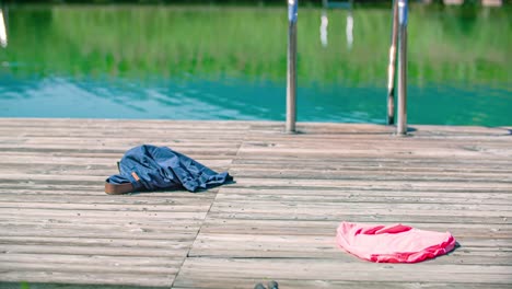 Se-Tira-Un-Par-De-Jeans-En-La-Cubierta-De-Natación-Y-Un-Hombre-Lo-Recoge