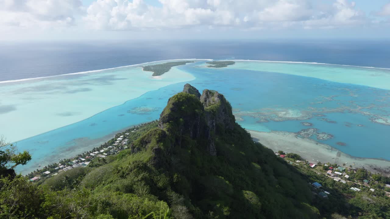 Landscape view of a lagoon and coral reef in a small green tropical pacific island from a viewpoint on a sunny day at Mount Teurafaatiu, Maupiti, French Polynesia.