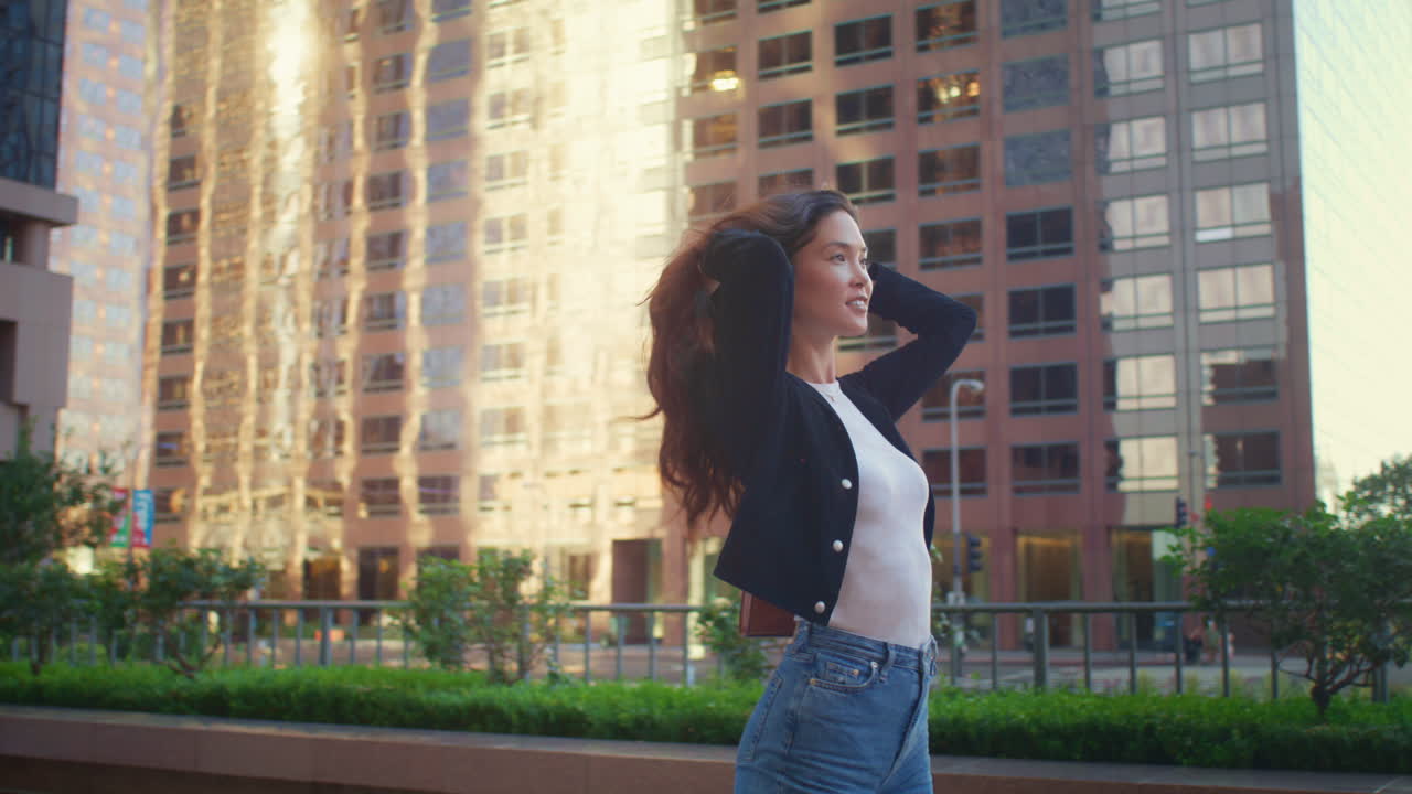 쾌활한 소녀는 시내 거리에서 회전합니다. 아시아 여성은 야외에서 는 것을 즐니다.