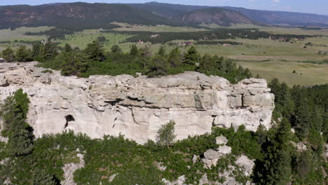 aerial views of a grassy plane heading to a beautiful rock formation in palmer lake colorado