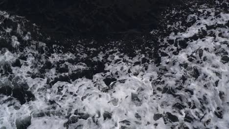 waves created by a moving ship with white foam rising up in a dark deep sea