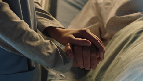 hospital nurse holding hand of old woman in bed comforting elderly patient sleeping recovering from illness medical professional at bedside giving encouragement health care support