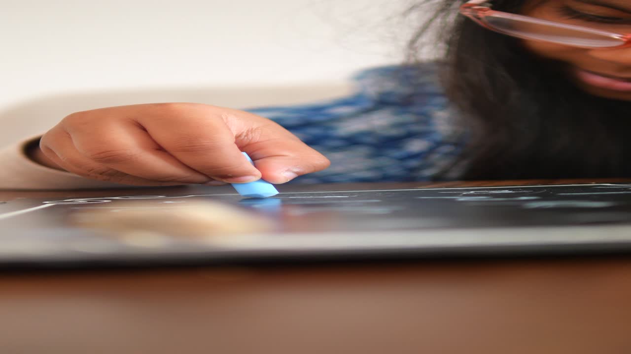 niña dibujando con tiza en una tabla