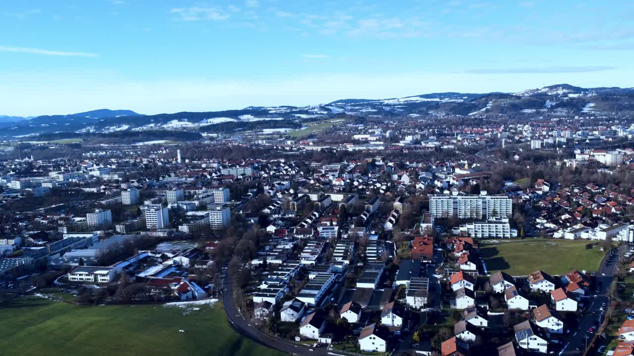 Peaceful city in southern Germany with chaotically laid out houses in the foreground, snow-covered hills in the background