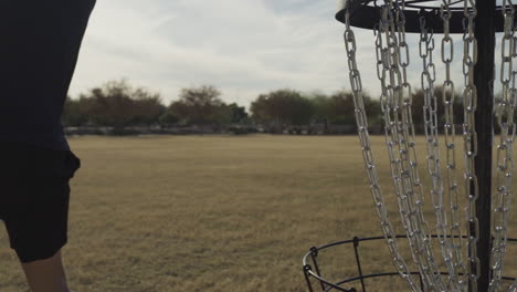 disc golfer throws forehand into open field right next to frolf basket in slow motion | disc golf