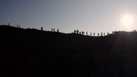 siluetas de personas en la cima del volcán mout batur en bali, indonesia, caminan a lo largo de la cresta del cráter, tiro aéreo a la derecha