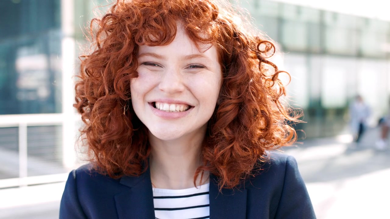 Portrait of a Smiling Young Woman with Curly Red Hair