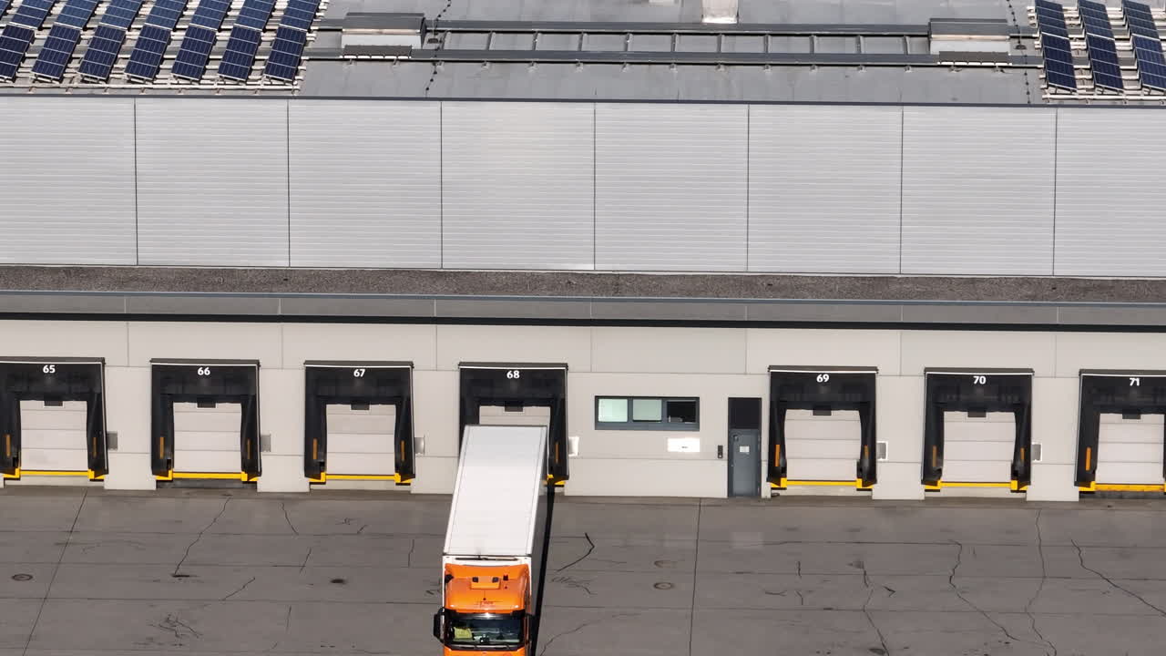 Trucks handle cargo at loading docks of a logistics center during daylight warehouse operations