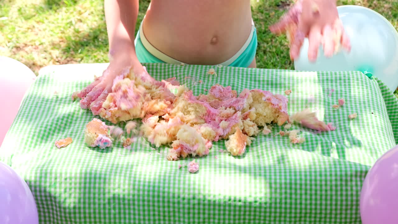 Cake smash birthday celebration by young girl using bare hands, telephoto slomo
