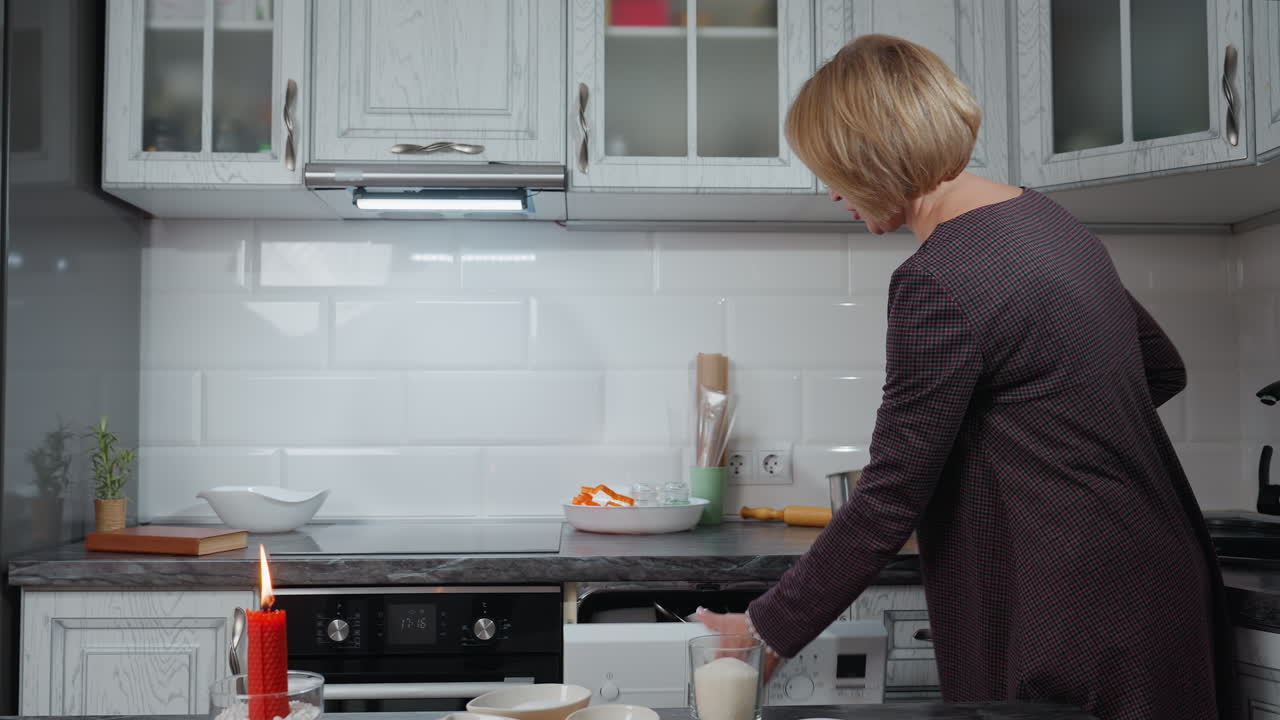 우아한 드레스를 입은 여성이 주방 캐비에 비를 놓고 테이블을 준비하는 동안 불타는 빨간 불, 설탕, 버터 및 향신료, 따뜻한 조명과 세련된 장식으로 현대 주방