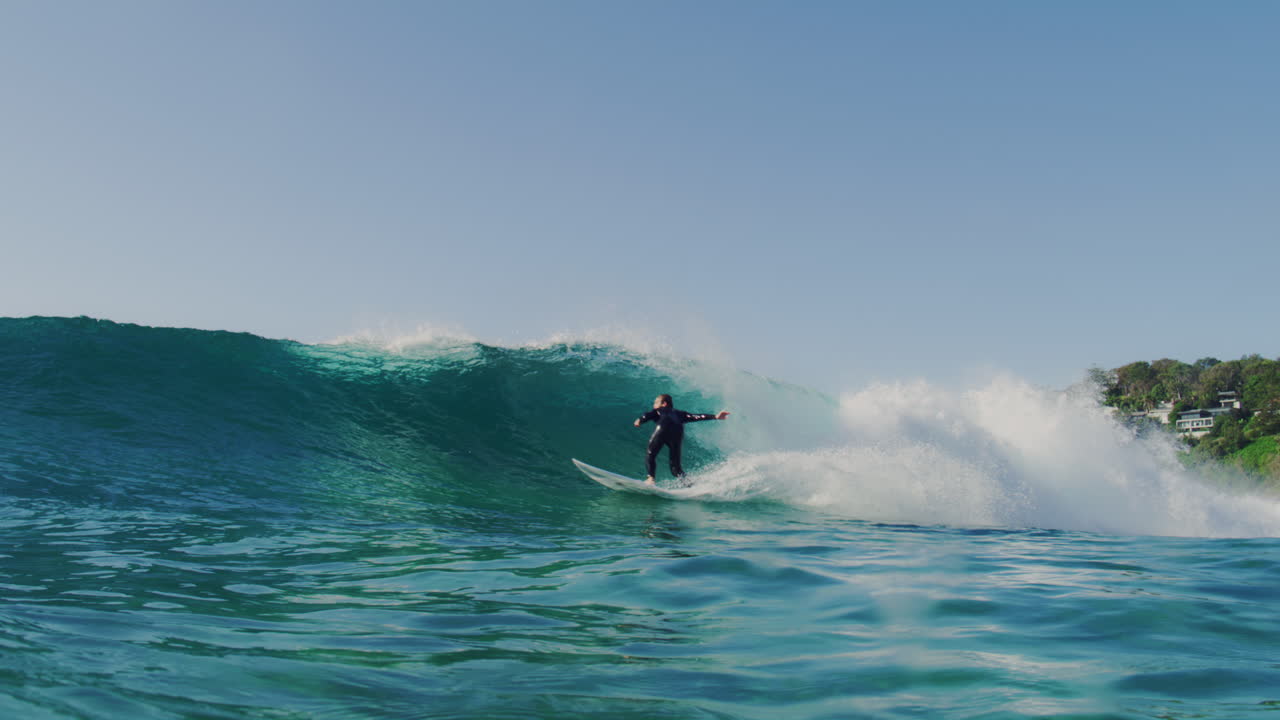 Slow motion view of surfer in the morning as they glide and catch beautiful waves cutting back into stunning displays of skill
