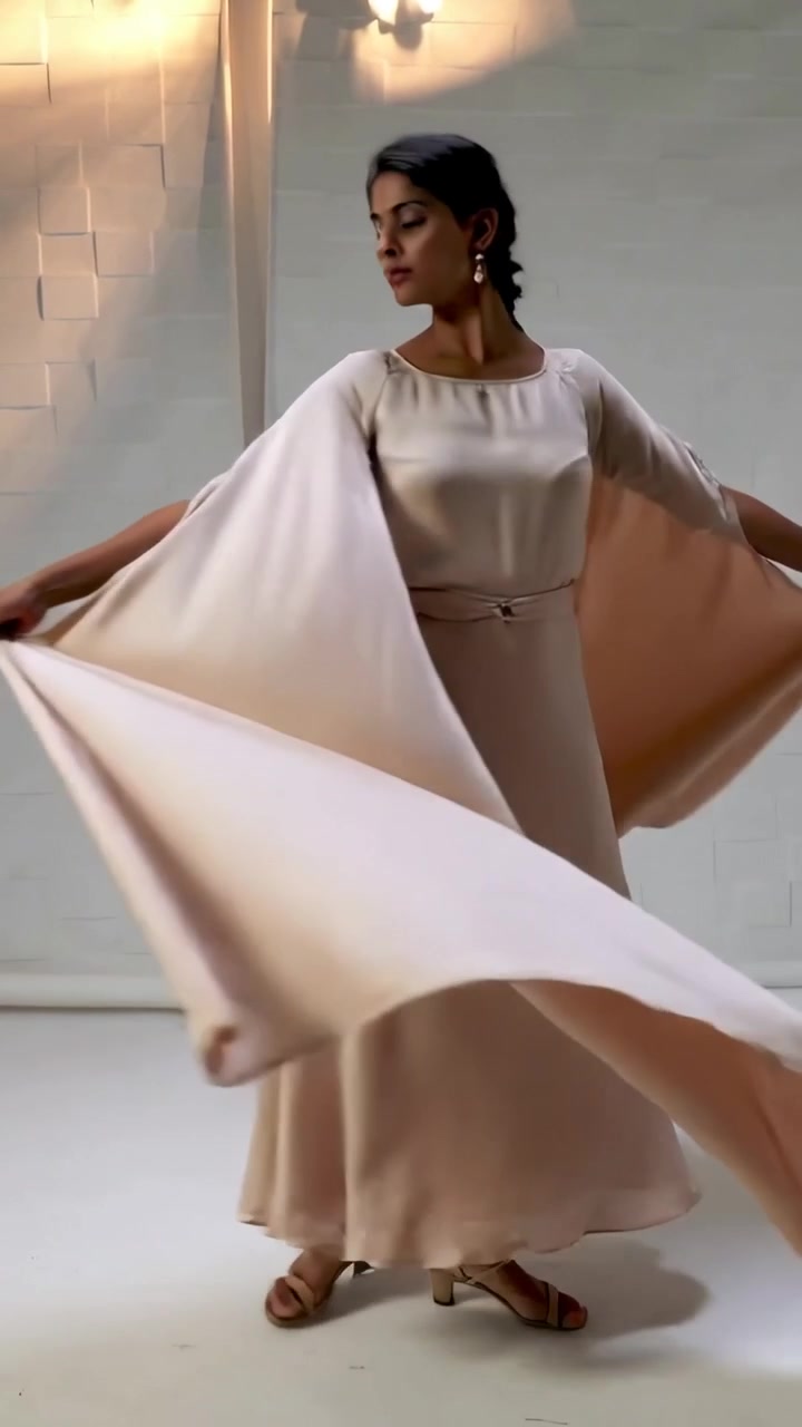 Video verticale: Modella indiana che inizia a girare lentamente in studio, mostrando un abito a cappa beige.